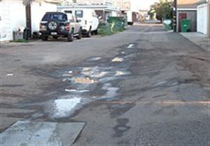 Alley with patched pavement and puddles
